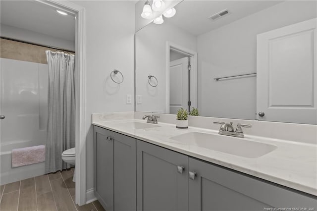 full bathroom featuring a sink, visible vents, toilet, and double vanity