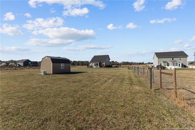 view of yard featuring a rural view, a storage shed, an outdoor structure, and fence