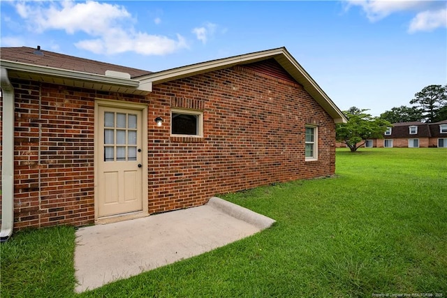 property entrance featuring a yard and brick siding