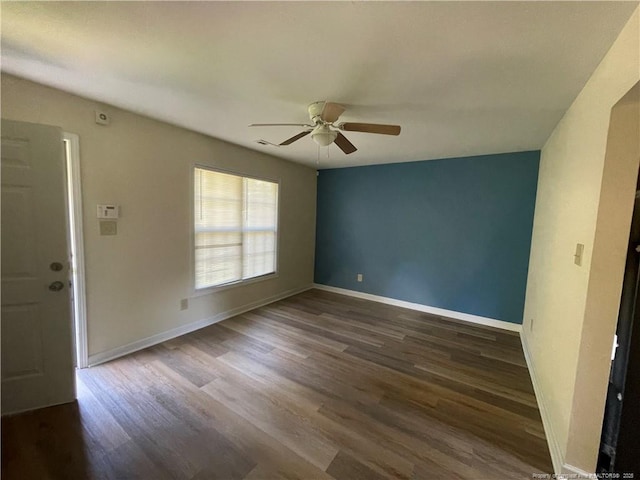 spare room featuring ceiling fan, baseboards, and wood finished floors