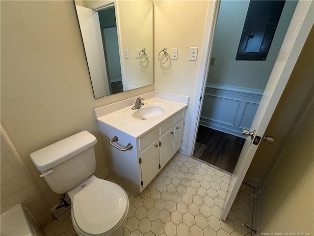 bathroom with toilet, wainscoting, vanity, and a decorative wall