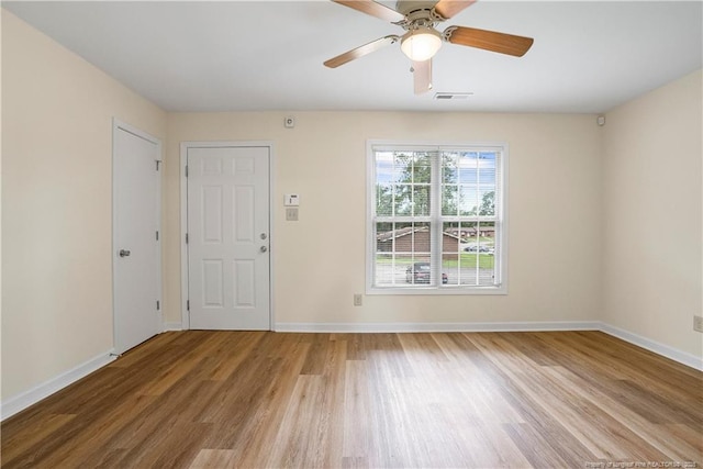 spare room featuring baseboards, visible vents, light wood finished floors, and ceiling fan