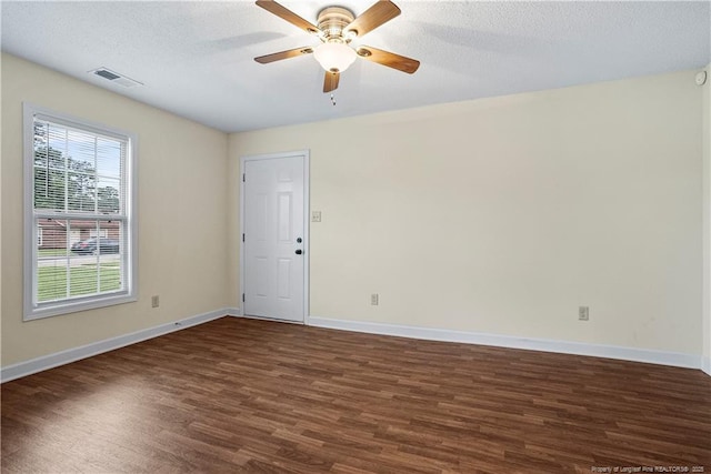 spare room with a ceiling fan, baseboards, visible vents, dark wood-type flooring, and a textured ceiling