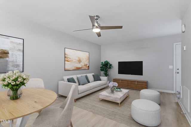 living area featuring visible vents, baseboards, wood finished floors, and a ceiling fan