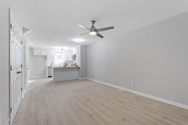 unfurnished living room featuring visible vents, baseboards, light wood-style flooring, and a ceiling fan