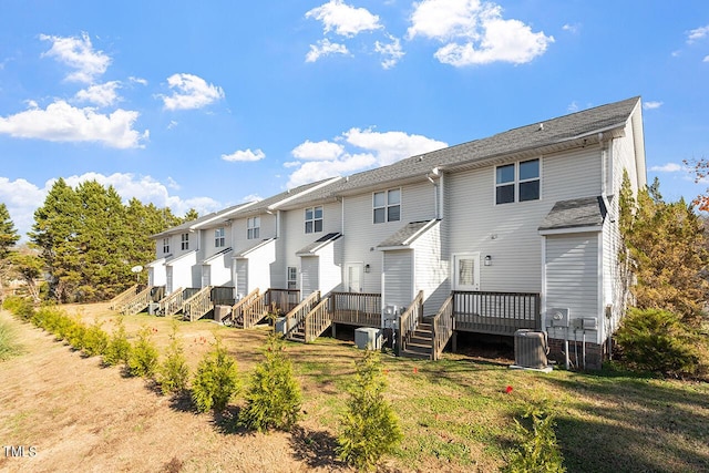 back of property featuring a lawn, a wooden deck, and central AC