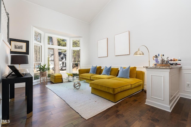 living room with dark wood finished floors, a decorative wall, ornamental molding, and wainscoting