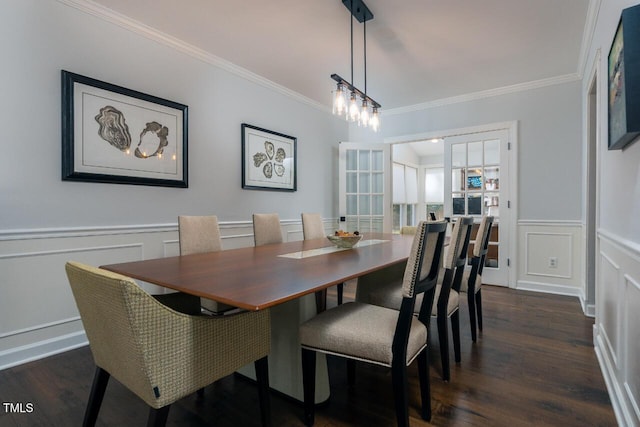 dining room with dark wood finished floors, a decorative wall, a wainscoted wall, and ornamental molding