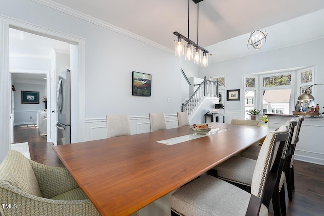 dining area featuring dark wood finished floors, a wainscoted wall, stairs, and ornamental molding