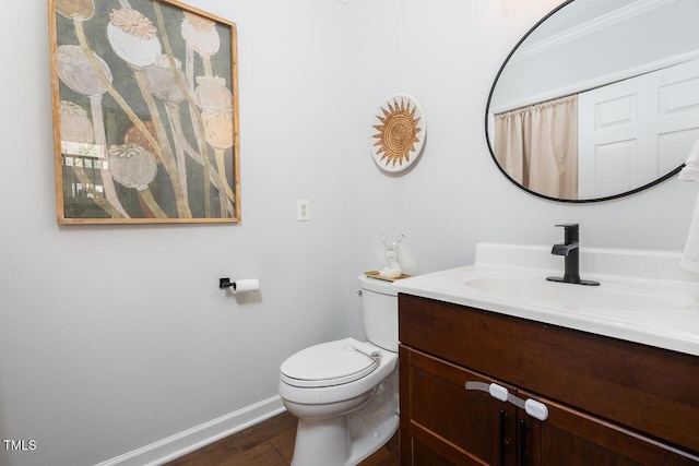 bathroom featuring toilet, vanity, baseboards, and wood finished floors