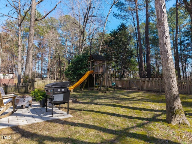 view of yard with fence, an outdoor fire pit, a patio, and a playground