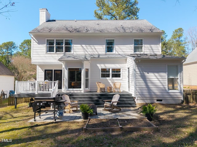 back of property featuring a wooden deck, a chimney, a yard, crawl space, and a patio