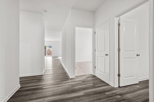 hallway with dark wood finished floors and baseboards