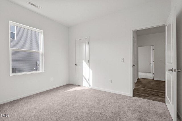 unfurnished bedroom with carpet, visible vents, and baseboards