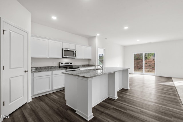 kitchen featuring light stone counters, white cabinetry, stainless steel appliances, and dark wood-type flooring