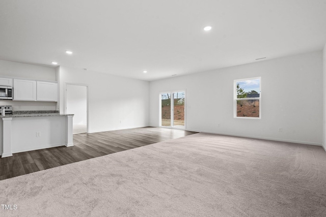 unfurnished living room with dark colored carpet and recessed lighting