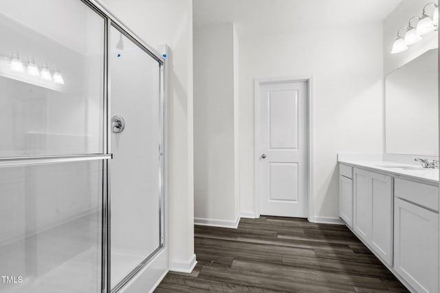 bathroom featuring baseboards, vanity, wood finished floors, and a shower stall