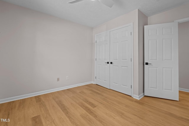 unfurnished bedroom with a closet, light wood-style flooring, a textured ceiling, and baseboards