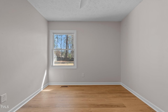 unfurnished room with visible vents, a textured ceiling, baseboards, and light wood-style floors