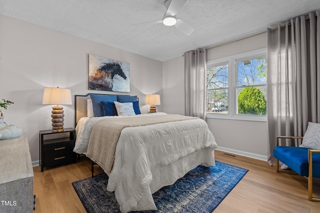 bedroom featuring visible vents, baseboards, a textured ceiling, and light wood-style flooring