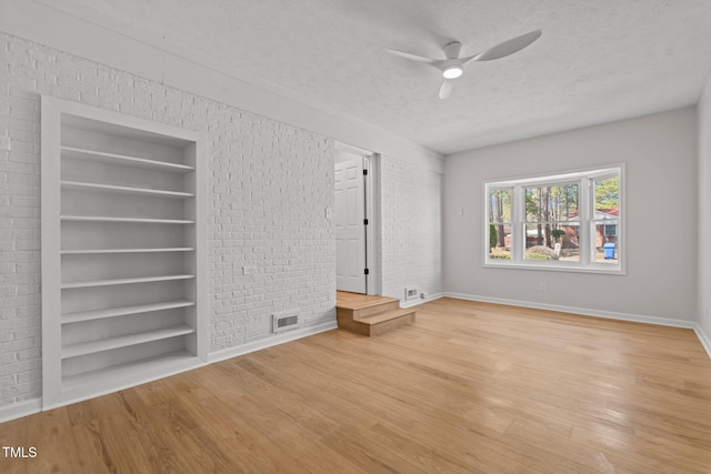 interior space with light wood-type flooring, visible vents, baseboards, and a textured ceiling