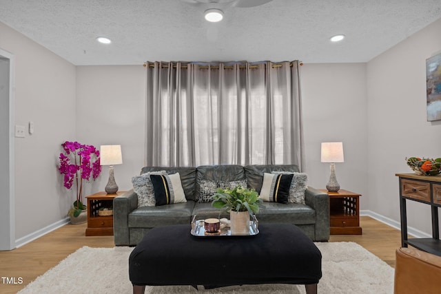 living area featuring a textured ceiling, baseboards, and wood finished floors