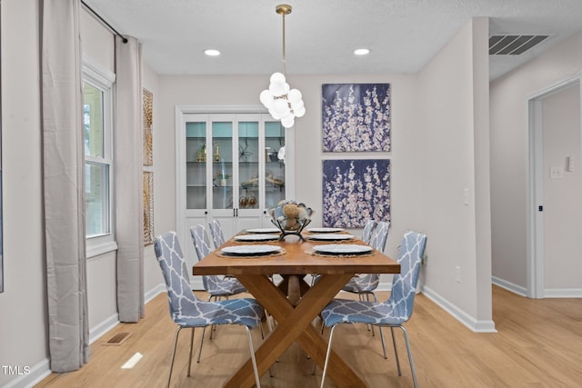 dining area with baseboards, visible vents, recessed lighting, light wood-type flooring, and a chandelier