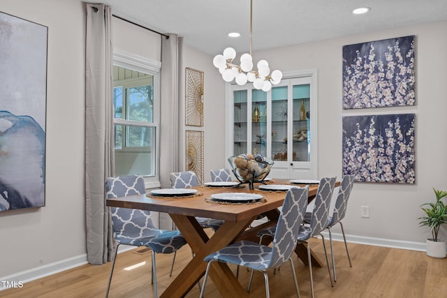 dining area featuring a notable chandelier, light wood-type flooring, and baseboards