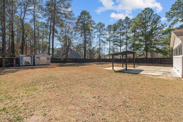 view of yard featuring a detached carport, an outbuilding, a fenced backyard, a storage shed, and a patio area