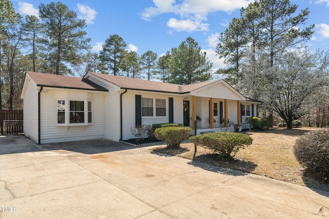 single story home featuring fence, driveway, roof with shingles, a porch, and brick siding