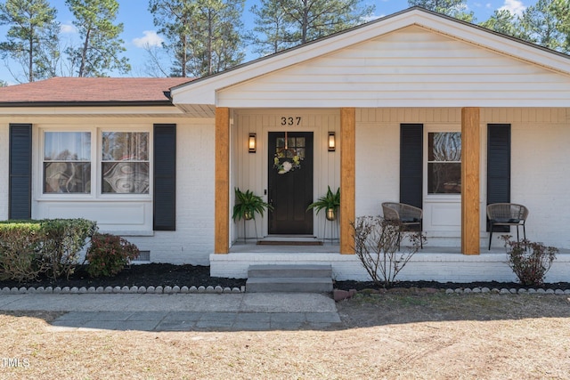 view of front of house featuring a porch, brick siding, and a shingled roof