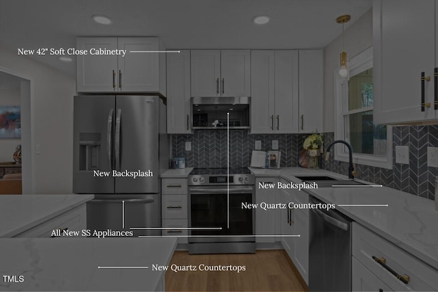 kitchen with hanging light fixtures, appliances with stainless steel finishes, white cabinetry, and a sink