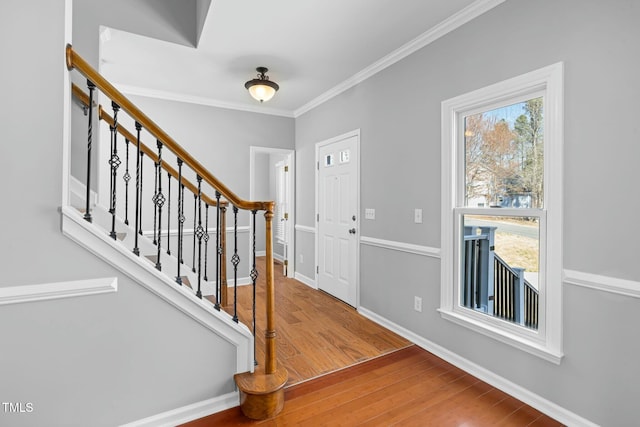 foyer featuring crown molding, stairway, wood finished floors, and baseboards