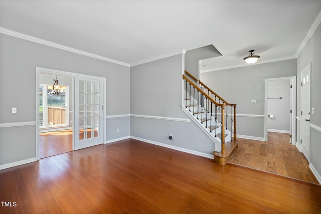 empty room featuring crown molding, stairs, an inviting chandelier, and hardwood / wood-style flooring