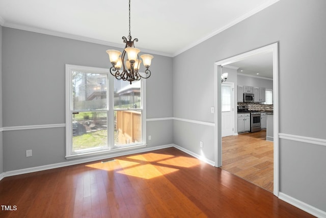 unfurnished dining area featuring a chandelier, plenty of natural light, ornamental molding, and hardwood / wood-style flooring