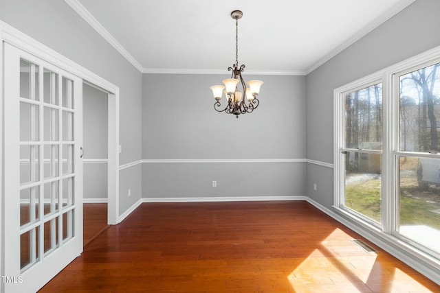 unfurnished dining area with a notable chandelier, wood finished floors, baseboards, and ornamental molding