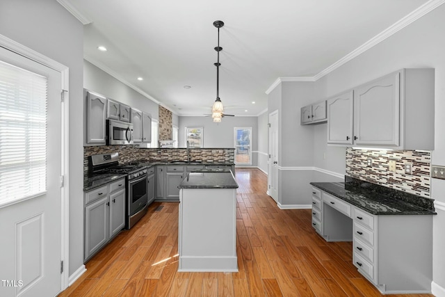 kitchen with light wood finished floors, a peninsula, gray cabinets, ornamental molding, and stainless steel appliances