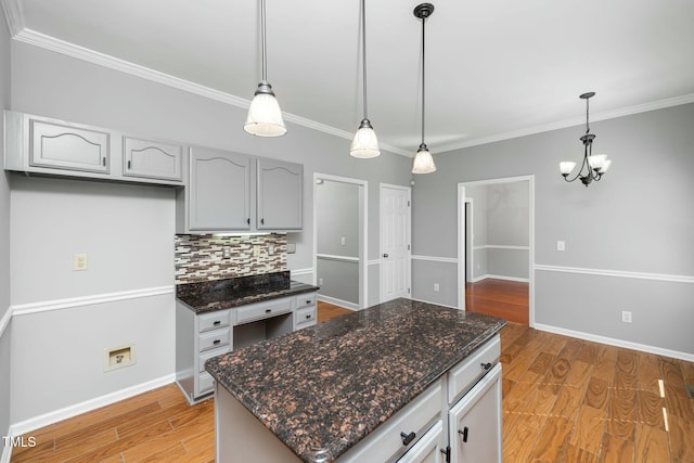 kitchen featuring light wood finished floors, ornamental molding, decorative light fixtures, tasteful backsplash, and a chandelier