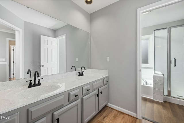 full bath with a sink, double vanity, wood finished floors, and a shower stall