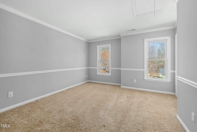 carpeted spare room featuring visible vents, attic access, baseboards, and ornamental molding