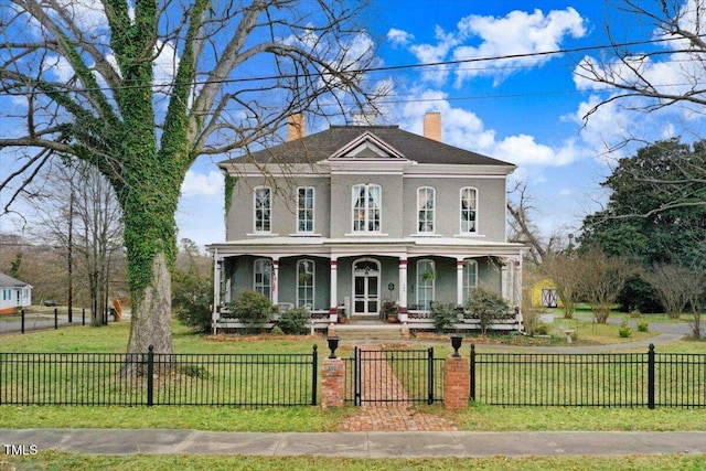 italianate house with a fenced front yard, a porch, a front lawn, and stucco siding