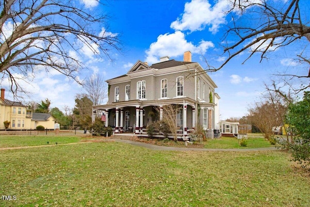 view of front facade with a porch, a chimney, and a front lawn