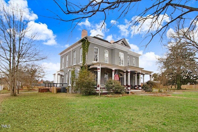 view of front of home featuring covered porch, a chimney, a front lawn, and stucco siding