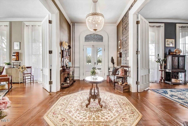 foyer entrance with an inviting chandelier, crown molding, radiator, and wood finished floors