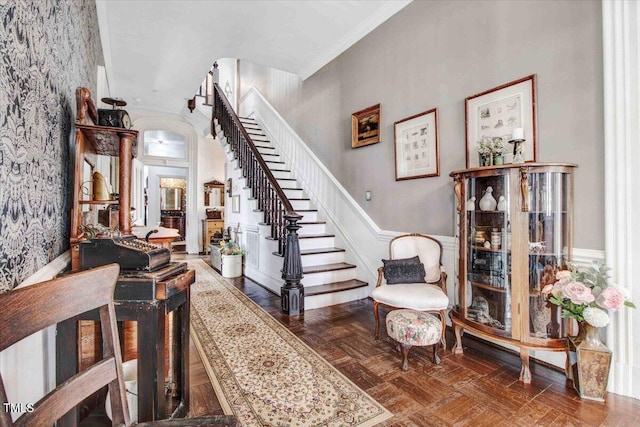 foyer entrance featuring stairs, ornamental molding, and wainscoting