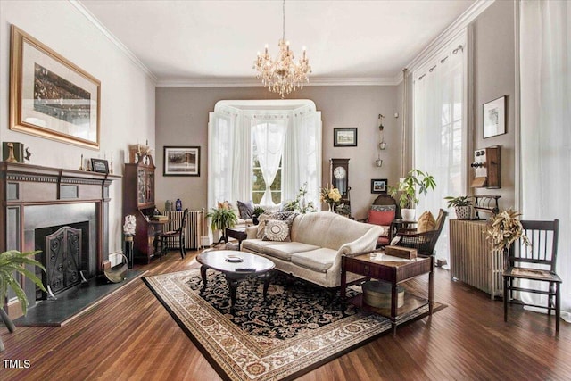 living room featuring dark wood-style floors, a fireplace with raised hearth, crown molding, and an inviting chandelier