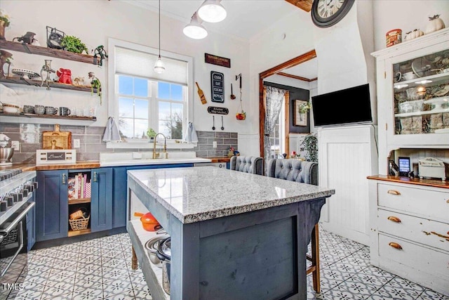 kitchen with hanging light fixtures, crown molding, blue cabinets, and open shelves