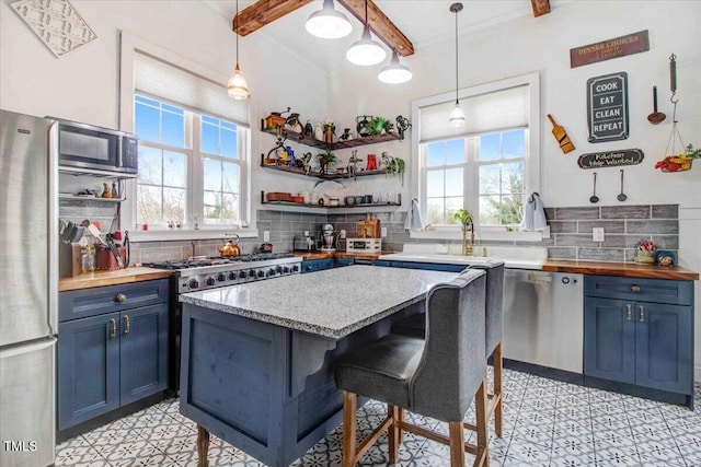 kitchen with tasteful backsplash, blue cabinetry, wooden counters, beamed ceiling, and stainless steel appliances