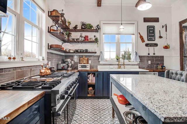 kitchen with blue cabinetry, open shelves, a sink, backsplash, and high end range