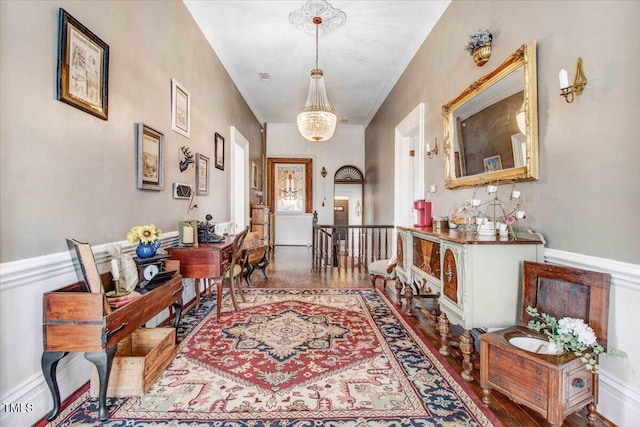 foyer entrance featuring a wainscoted wall, a notable chandelier, and ornamental molding